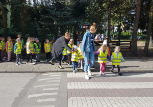 Przedszkolaki ze swoimi ciociami przechodzą przez przejście dla pieszych
